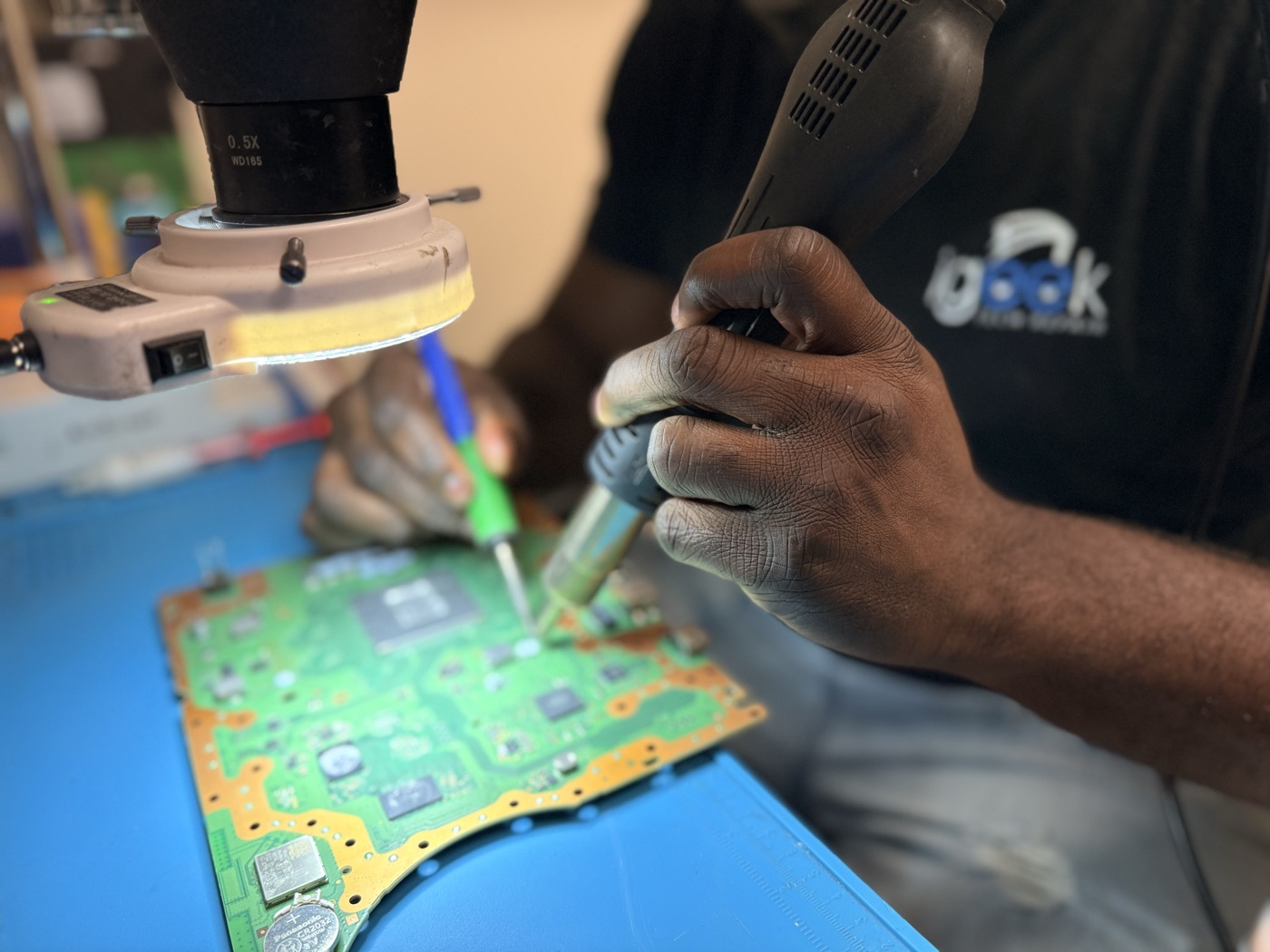 Microsoldering a circuit board under the microscope at the iGeek repair bench