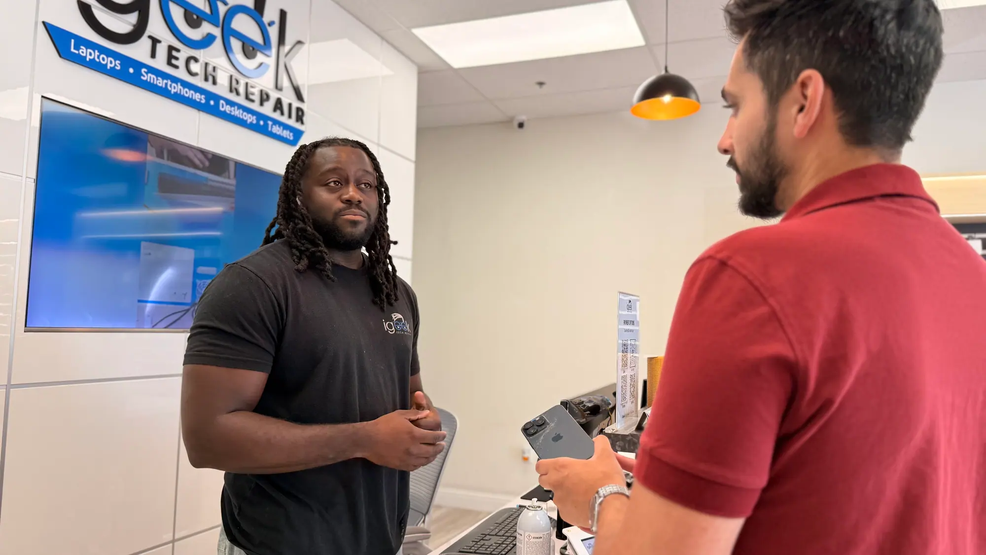 iGeek technician talking a customer through a phone repair at the front counter