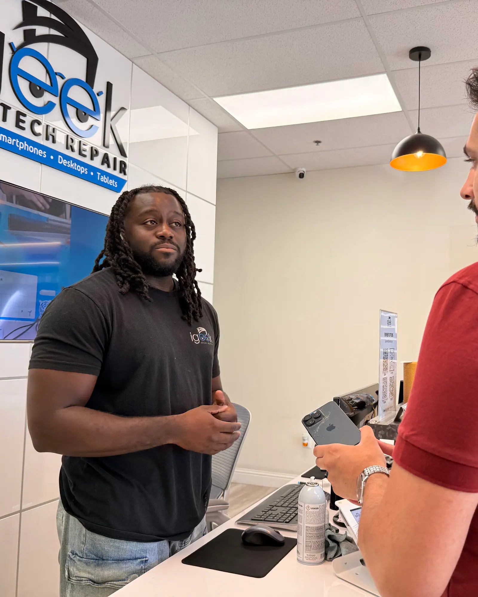 iGeek technician talking a customer through a phone repair at the front counter