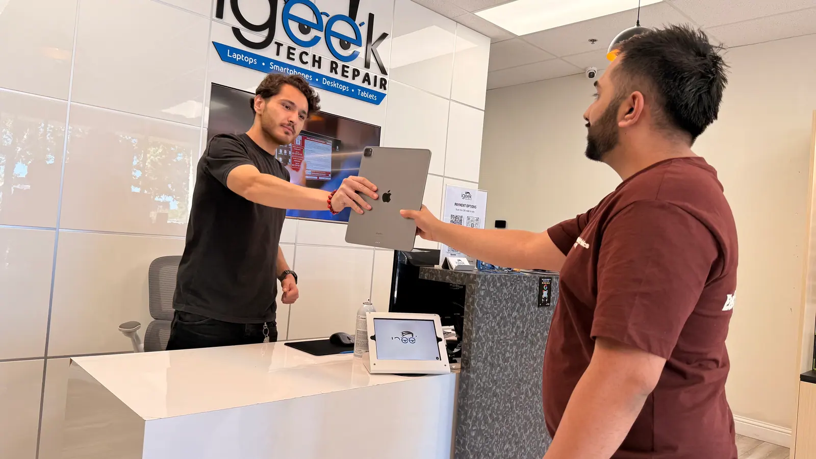 Customer handing an iPad across the iGeek front counter