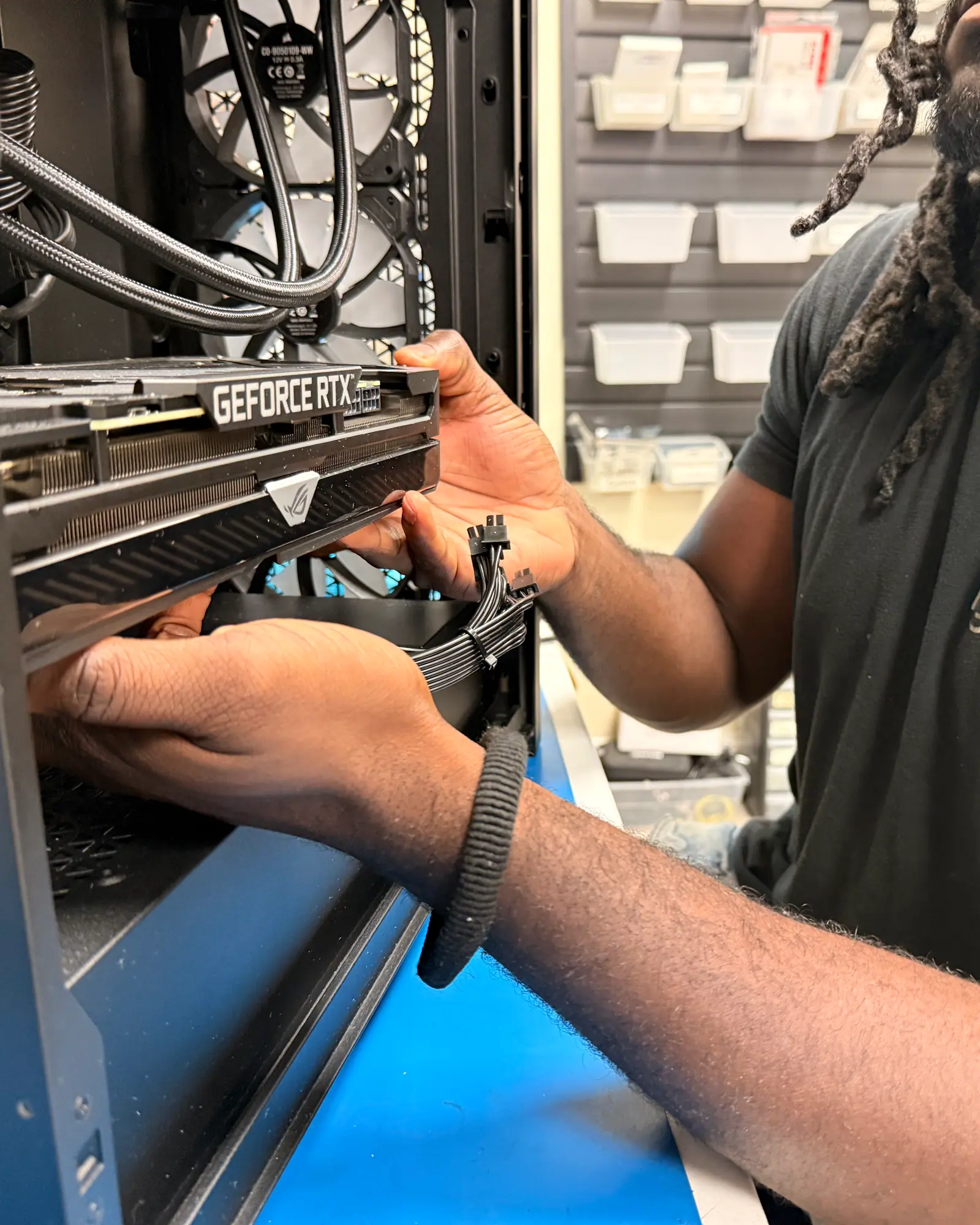 A technician lowering a graphics card into an open desktop tower