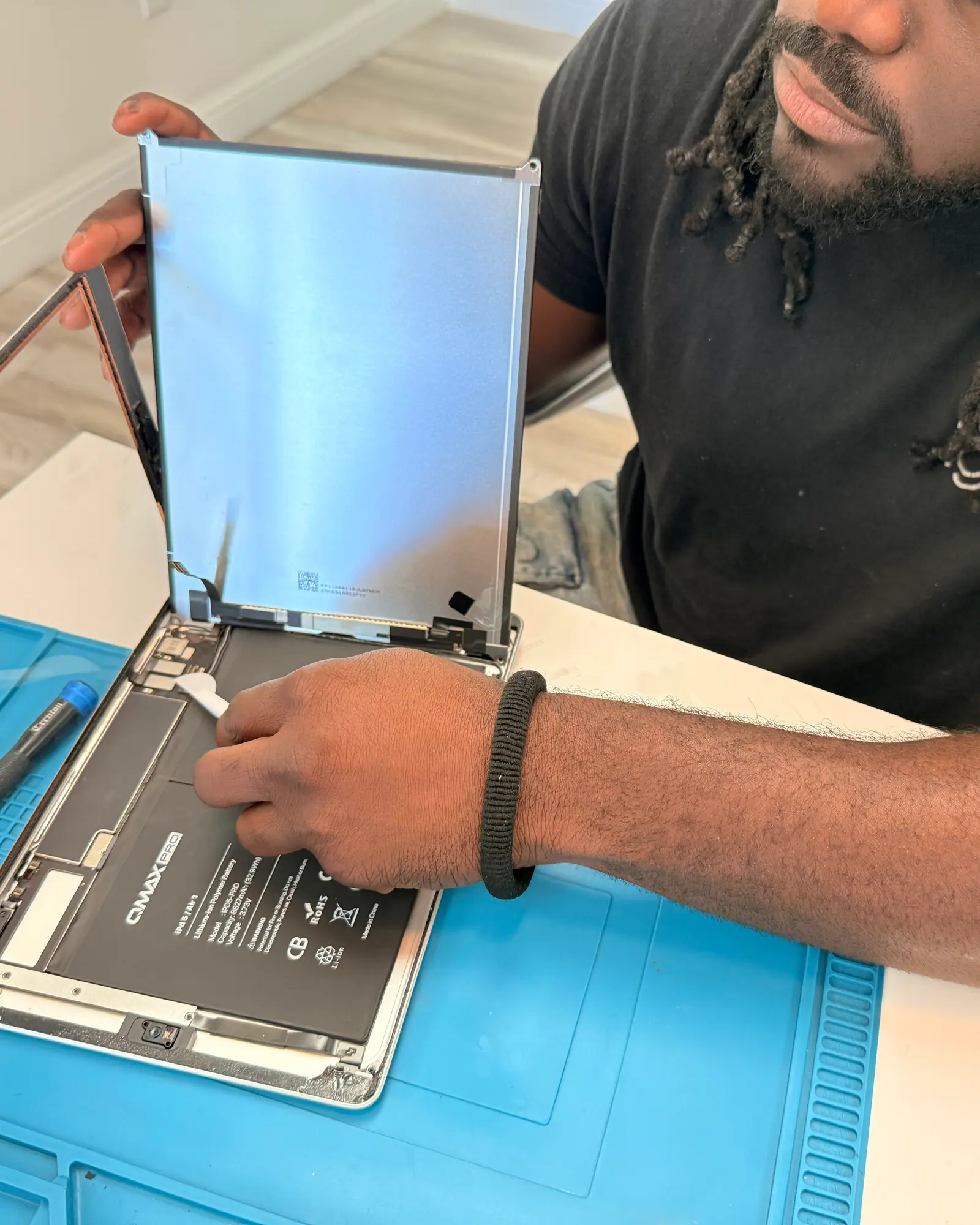 A laptop opened on the bench with its bottom cover removed and the battery exposed