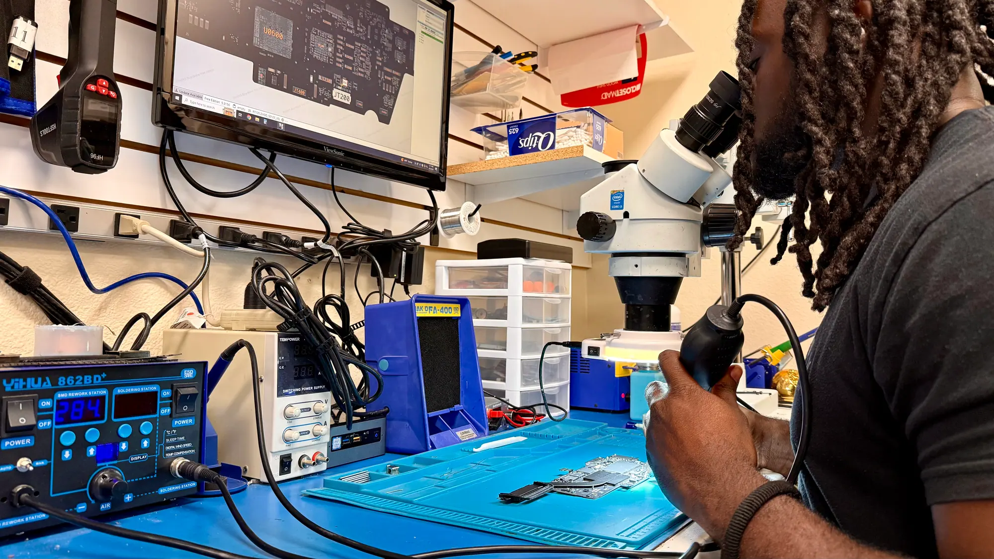 iGeek technician looking through a stereo microscope at the board repair station