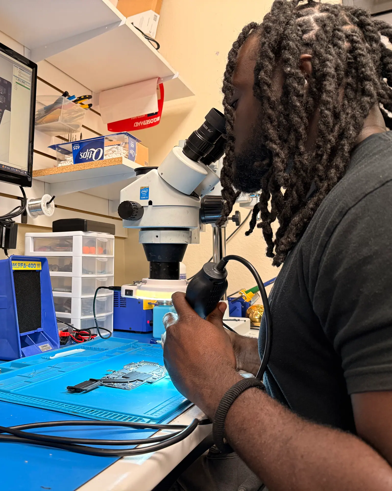 iGeek technician looking through a stereo microscope at the board repair station