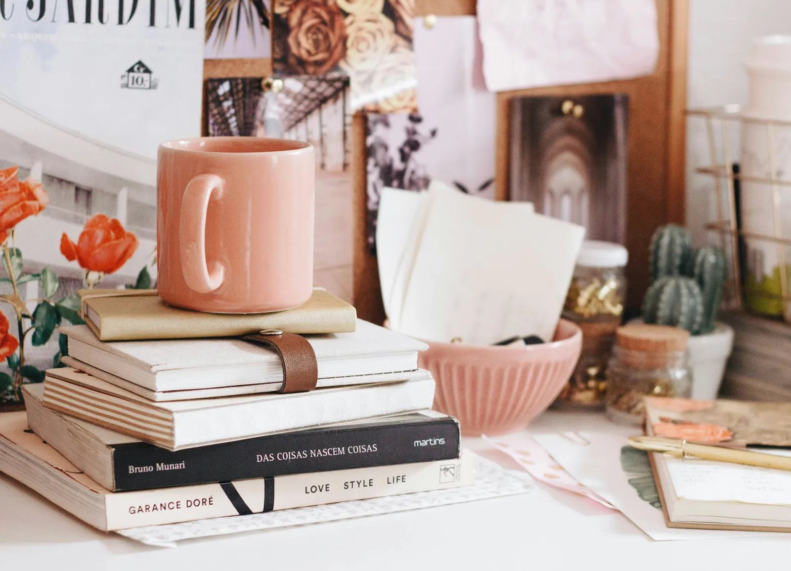 A pink coffee mug resting on a stack of books on a desk