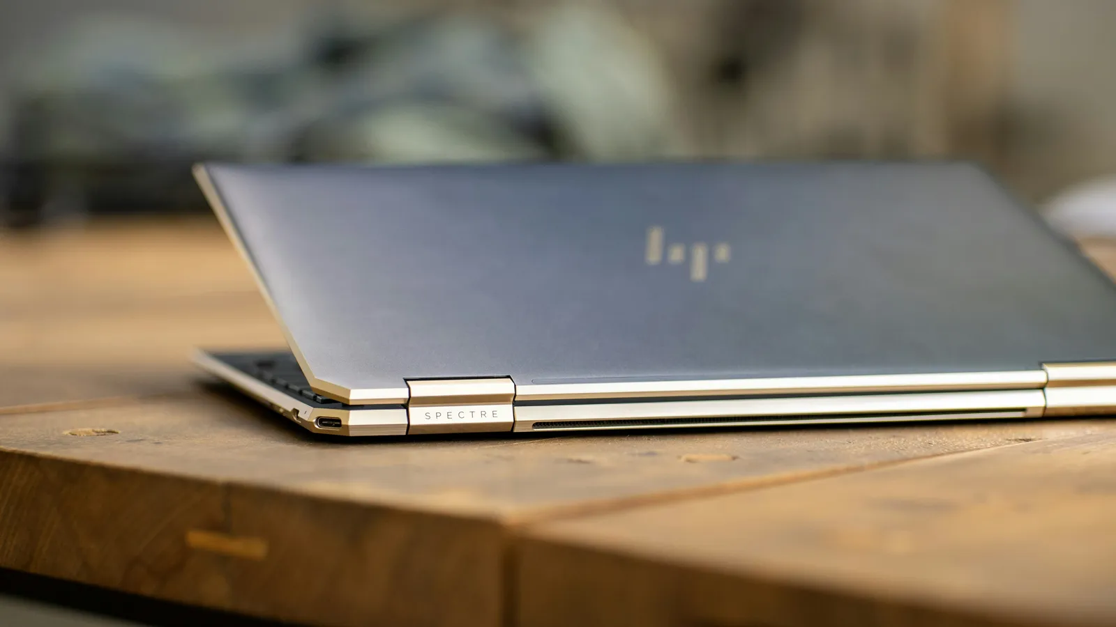 A closed HP Spectre laptop on a wooden table